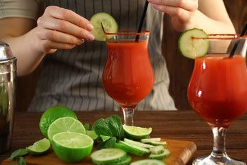 Woman making cocktail with tequila at table