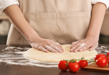 Woman preparing pizza at kitchen table