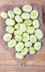 Green fresh broad beans on old wooden table.