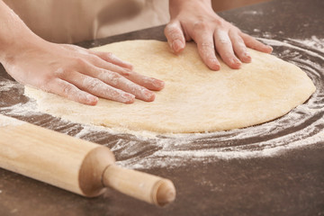 Woman preparing pizza at kitchen table