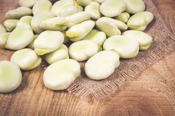 Green fresh broad beans on old wooden table.