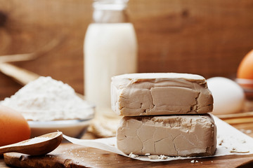 Fresh yeast and ingredients for baking on vintage kitchen background. Product for preparing pizza or bread.