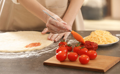 Obraz na płótnie Canvas Woman preparing pizza at kitchen table