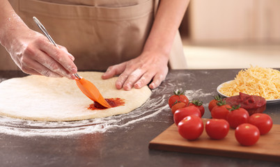 Woman preparing pizza at kitchen table