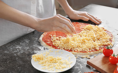 Woman preparing pizza at kitchen table