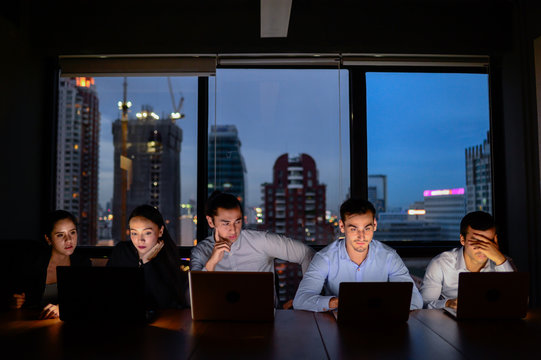 three businessman and two businesswoman working with computer overtime at night and low light