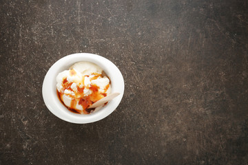 Fototapeta na wymiar Bowl with vanilla ice cream and caramel sauce on table