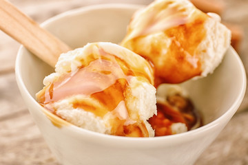 Bowl with vanilla ice cream and caramel sauce, closeup