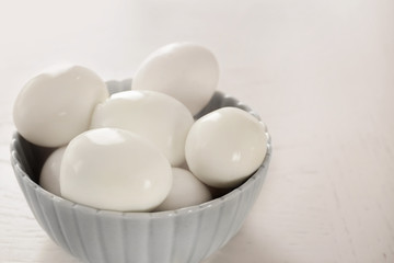 Bowl with hard boiled eggs on light background. Nutrition concept