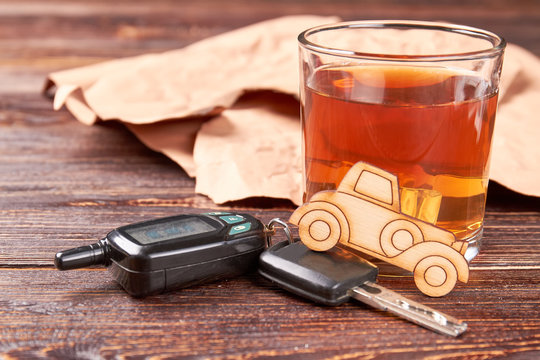 Car, whisky, automobile keys. Brandy with ice, car, automobile keys on wooden background. Concept of drunk drivers accidents.