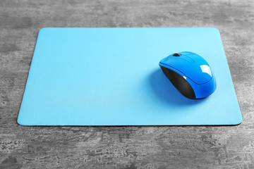 Blank mat and wireless mouse on textured background © Africa Studio