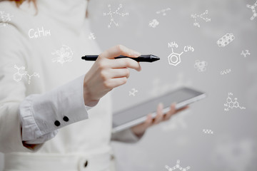 Woman chemist working with chemical formulas on grey background.