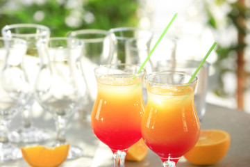 Glasses of delicious tequila sunrise cocktails on blurred background