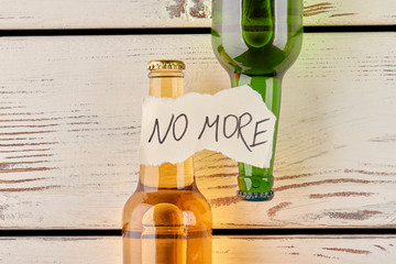 No more alcohol and drunkenness. Message, two bottles, old wooden background.