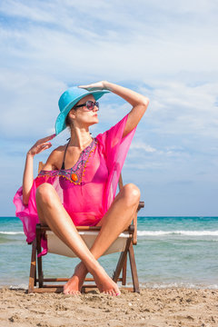 Woman sitting on a deck chair at the beach