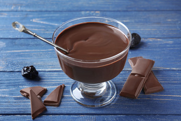 Glass dessert bowl with delicious chocolate sauce and spoon on wooden table