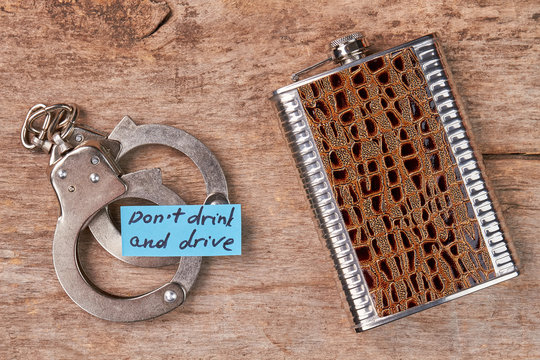 Metal handcuffs, paper message, hip flask. Law punishment for drunk drivers.