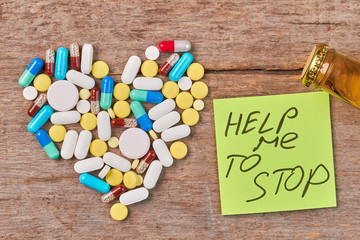 Help overcome alcohol addiction. Pills shaped heart, message, bottle, wooden background.