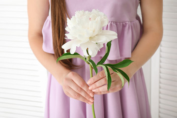 Young woman holding beautiful peony flower on light background