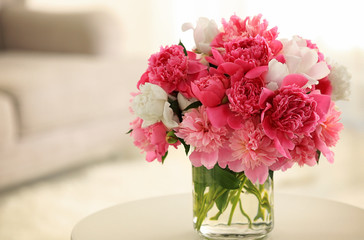 Glass vase with beautiful peonies on table