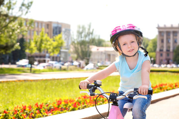 Fototapeta na wymiar Cute little girl riding bicycle outdoors on sunny day