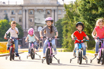 Fototapeta premium Cute little children riding bicycles outdoors on sunny day