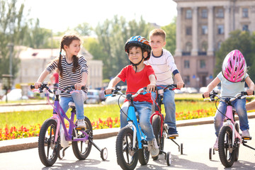 Cute little children riding bicycles outdoors on sunny day