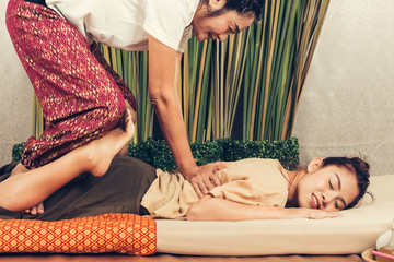 Young Girl get Thai style massage by Woman for body therapy - obrazy, fototapety, plakaty