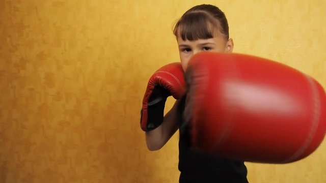 The little girl is boxing. The child is engaged in boxing.