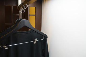 clothes hanger with black T-shirt in the wardrobe