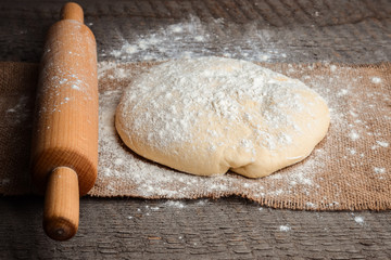 Ball of dough and rolling pin on rustic background