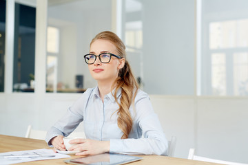 Young woman in eyeglasses and formalwear sitting in office