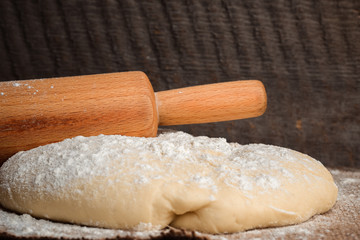 Fototapeta na wymiar Ball of dough and rolling pin on rustic background