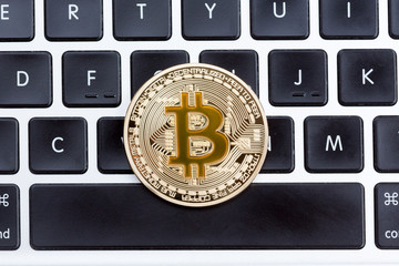 Cryptocurrency physical yellow bitcoin coin on black computer keyboard.