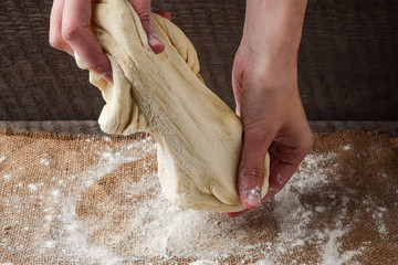 Hands prepare dough on a dark background