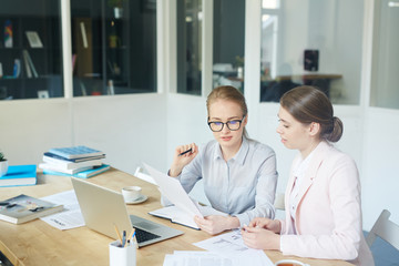 Economists discussing papers at meeting in office