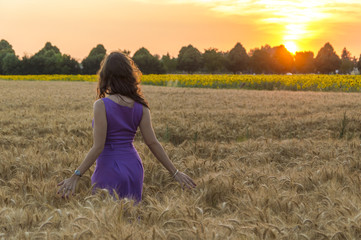 Young caucasian woman with long hairs at grain field at sunset