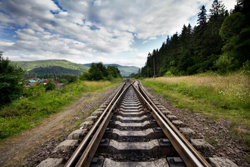 Fototapeta na wymiar Railroad Against Mountains And Beautiful Sky, Near Forest.