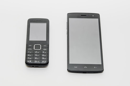 A modern smartphone and a old classic cell phone side by side on a white background.