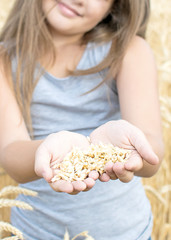 Wheat grains in the palms of a beautiful little girl. Symbol of life, peace, growth. Focus on palms of hands