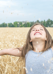 Laughing little girl throws up wheat grains. Concept of purity, growth, happiness