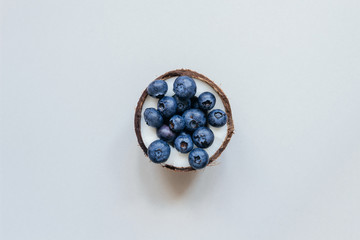 Obraz na płótnie Canvas Ripe coconut with blueberry on the gray background, top view