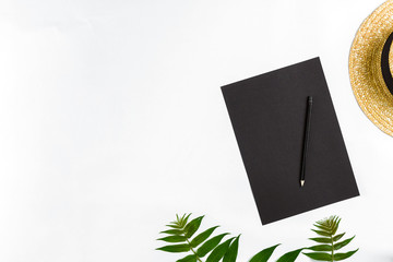 Natural composition with sketchbook and pencils on white table, decorated with green branches. Flat lay, top view, view from above