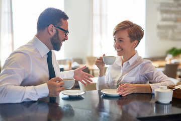 Happy business partners interacting by cup of coffee in cafe