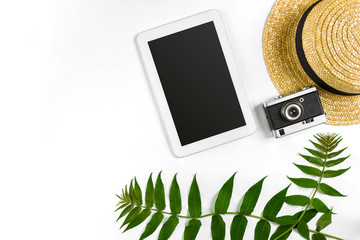 Straw hat with green leaves, tablet and old camera on white background, Summer background. Top view