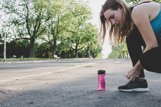 Preparing For Running. Young Woman Tying Her Running Shoes In The Park