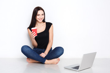 Fototapeta premium Woman using laptop sitting on the studio floor