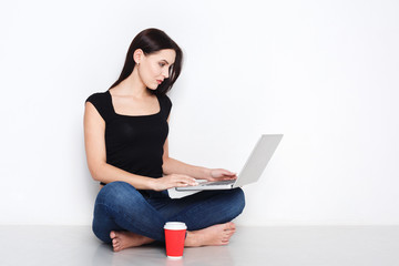 Naklejka premium Woman using laptop sitting on the studio floor