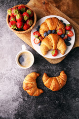 Delicious breakfast with fresh croissants and ripe berries on old marble background