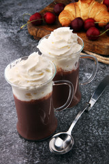 Iced coffee with whipped cream in tall glass and fresh croissant